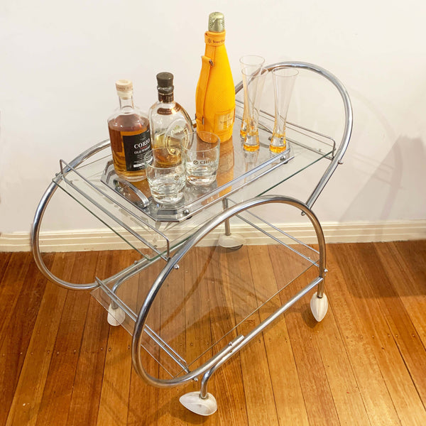 Australian art deco chrome and glass bar cart with bakelite wheel skirts