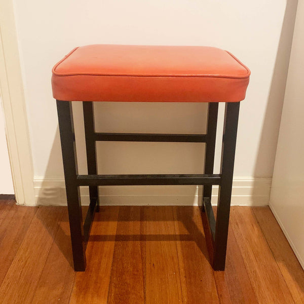 Upholstered mid century orange vinyl stool with black metal legs