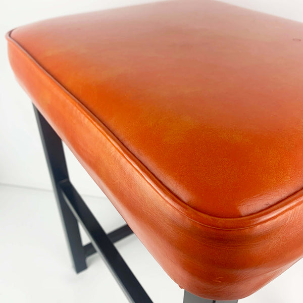 Upholstered mid century orange vinyl stool with black metal legs