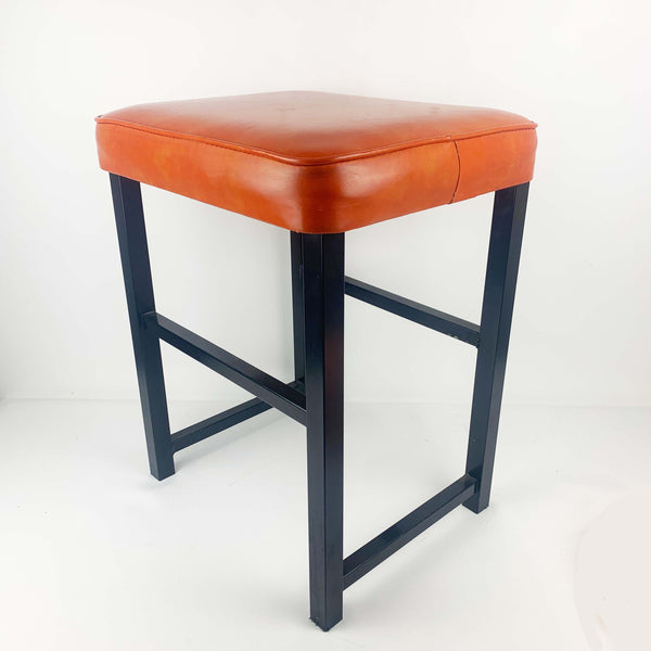 Upholstered mid century orange vinyl stool with black metal legs