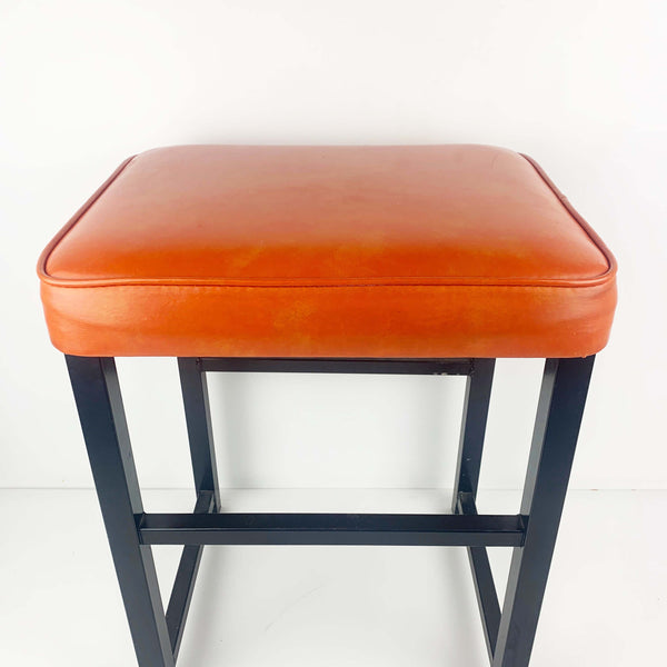 Upholstered mid century orange vinyl stool with black metal legs